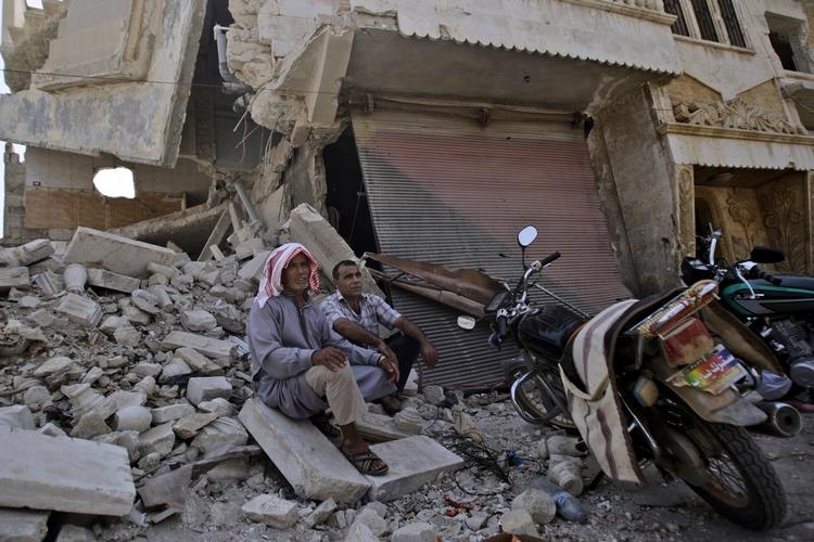 Murbrokker. To syriske mænd hviler ud ved en butik, der faldt sammen efter et angreb på et bageri i Azaz uden for Aleppo. 