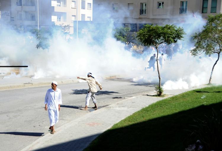 Oprør. Demonstranter udenfor den amerikanske ambassade i Tunis sender kasteskyts ind over muren. 