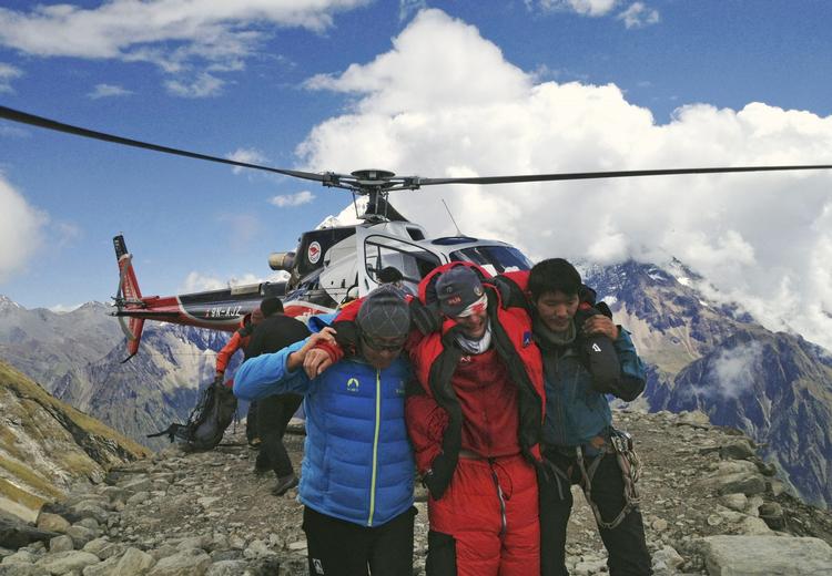 reddet. 13 bjergbestigere blev  reddet ud af snemasserne efter weekendens lavine i Nepal. Her er en af de sårede blevet fløjet ned fra bjerget. 