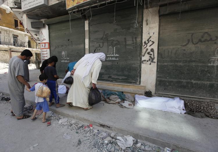 Borgerkrig. Endnu en dag - endnu flere dræbte. Forbipasserende kigger på tildækkede lig i millionbyen Aleppo. 