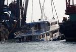 SAMMENSTØD. Den malflydende turbåd holdes nu oven vande af en bjærgningskran i Hongkongs havn. 