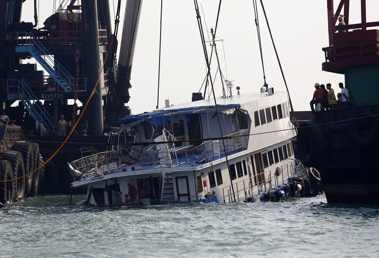 SAMMENSTØD. Den malflydende turbåd holdes nu oven vande af en bjærgningskran i Hongkongs havn. 