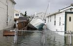 En sejlbåd ligger skyllet op mellem to oversvømmede huse i Lindenhurst, New York. 