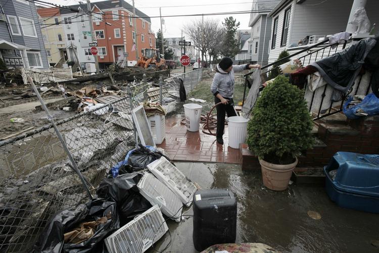 Ruth Dina Ticona er i gang med oprydningen efter Sandy i sin forhave til huset, der ligger ned til vandet i New York. 