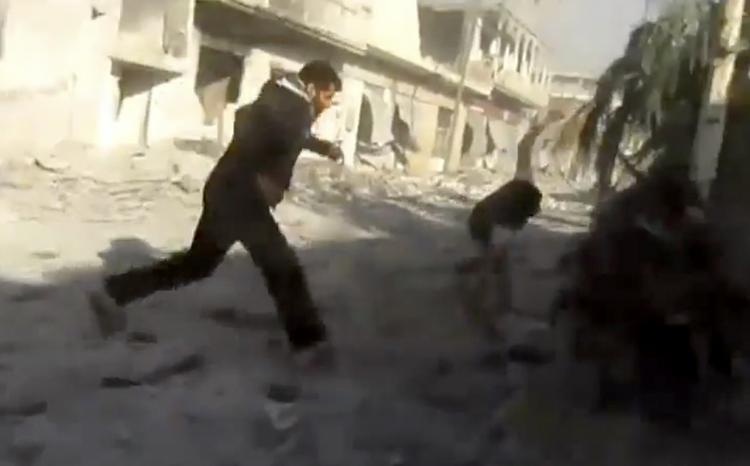 Oprør. En mand løber væk fra et område, der bliver bombet i Houla i Syrien. Billedet er fra et videoklip, der er blevet verificeret af nyhedsbureauet AP. 