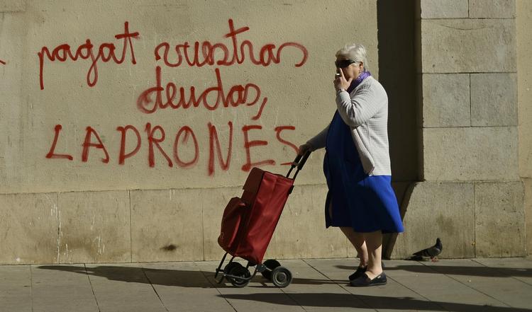 krise. 'Betal jeres gæld, tyve', står der på graffitien, som den spanske kvinde passerer i Barcelona. Spanien tegner sig for den højeste ledighedsprocent i den nye økonomiske prognose fra EU-Kommissionen. 