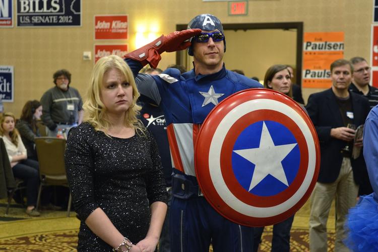 Skylddebat. Jon 'Captain America' Angell gør honør, mens Mitt Romney holder nederlagstale natten til onsdag. Billedet er fra republikanernes valghovedkvarter i Minnesota. Siden er republikanerne begyndt at debattere årsagen tli nederlaget. 