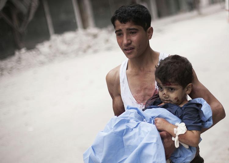 Kvæstet. En teenagedreng bærer et såret barn væk efter et granatangreb i Syriens største by, Aleppo. 