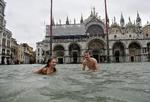 BADEFERIE. En ung mand og en kvinde svømmer på den oversvømmede Markusplads i Venedig. 