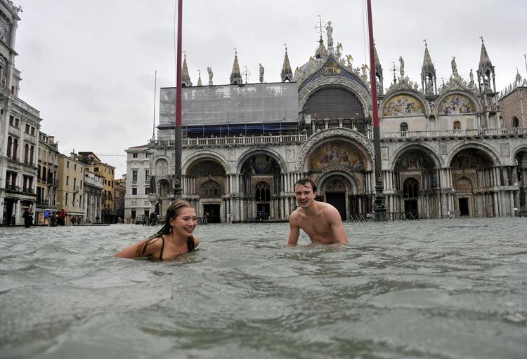 BADEFERIE. En ung mand og en kvinde svømmer på den oversvømmede Markusplads i Venedig. 