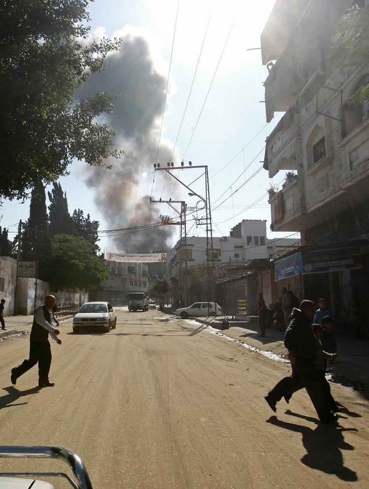Dækning. Indbyggere i Gaza By løber, mens en bombe falder i baggrunden. 