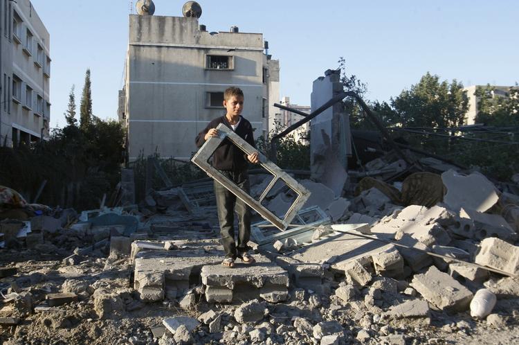 Ruiner. En palæstinensisk dreng holder en vinduesramme foran et ødelagt hus i Gaza City efter nye kampe mellem Hamas i Gaza og den israelske hær. 