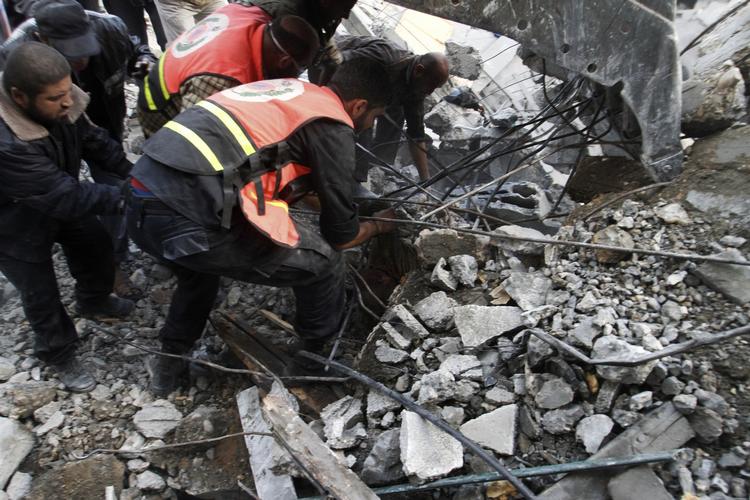 Murbrokker. Redningsarbejdere bjærger en lille piges lig fra den ramte bygning. 