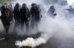 Optøjer. Politifolk kæmper for ikke at blive ramt af tåregas kastet af demonstranter. 
