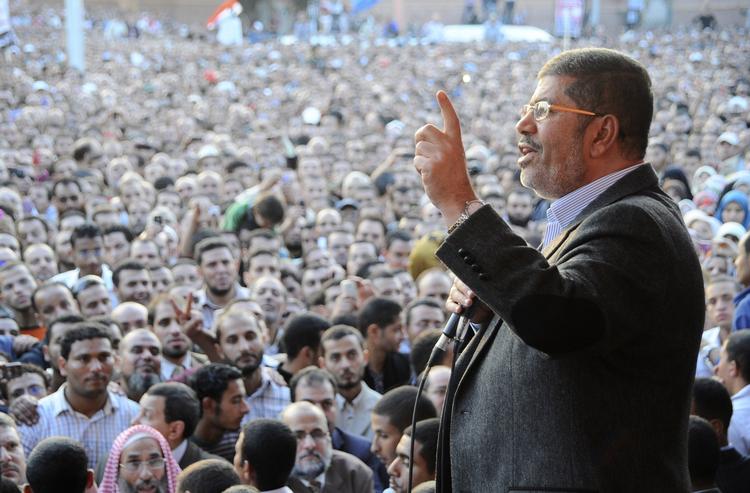 MAGTKAMP. Mange egyptere er gået på gaden for at protestere mod, at landets præsident Mohammed Morsi får mere magt. Her ses han på et officielt foto tale til sine tilhængere uden for præsidentpaladset i Kairo. 