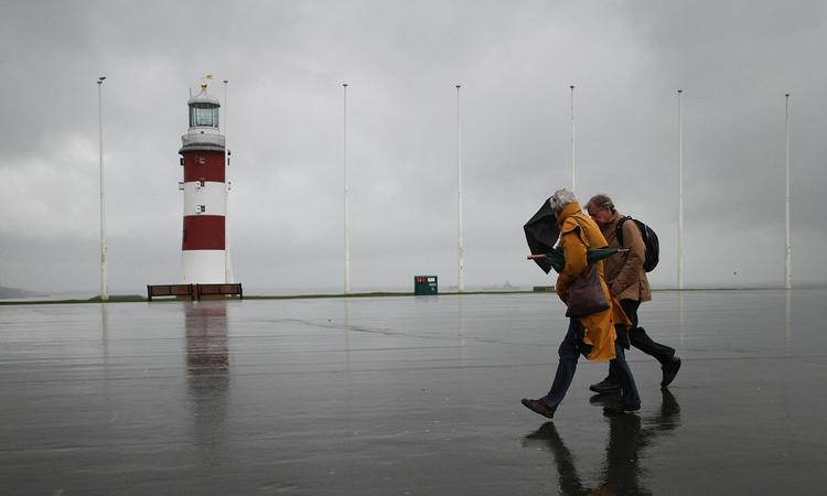 MODVIND. Spadserende i Plymouth trodser vinden og vandet. 