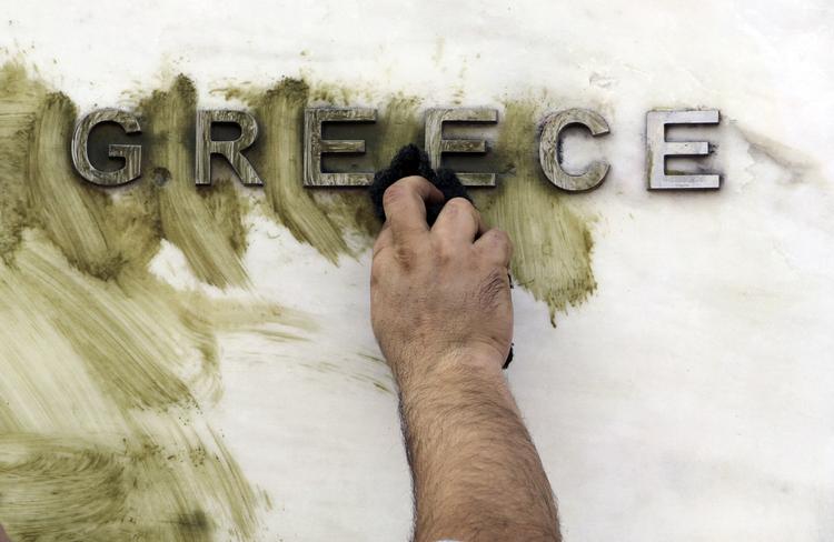 Pletrens. En mand fjerner grafitti fra Bank of Greeces facade. I nat fik det trængte land bevilget milliardlån af de øvrige eurolande og IMF. 