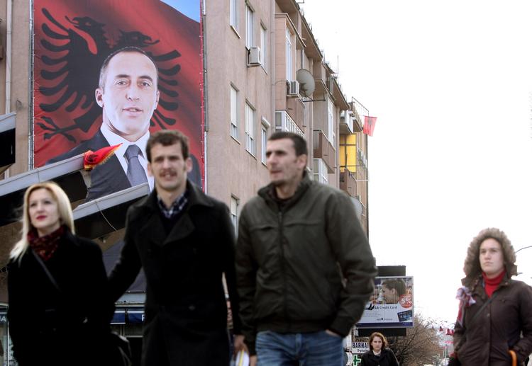 Folkehelt. Fodgængere i Kosovas hovedstad, Pristina, passerer et stort billede af Ramush Haradinaj. 
