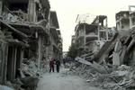KAMPE. Syrere i udbombet gade i Homs. Nu melder nyhedsbureauerne om flybombardementer af Damaskus' ydre forstæder. 