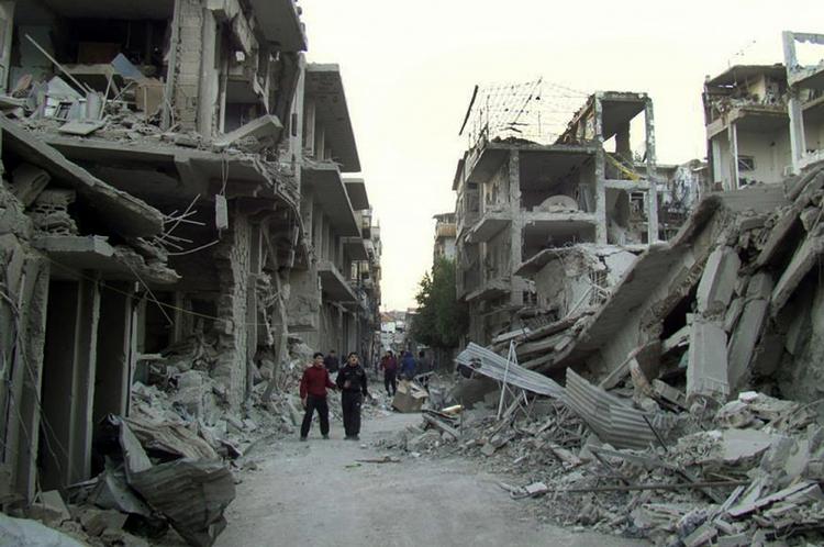 KAMPE. Syrere i udbombet gade i Homs. Nu melder nyhedsbureauerne om flybombardementer af Damaskus' ydre forstæder. 