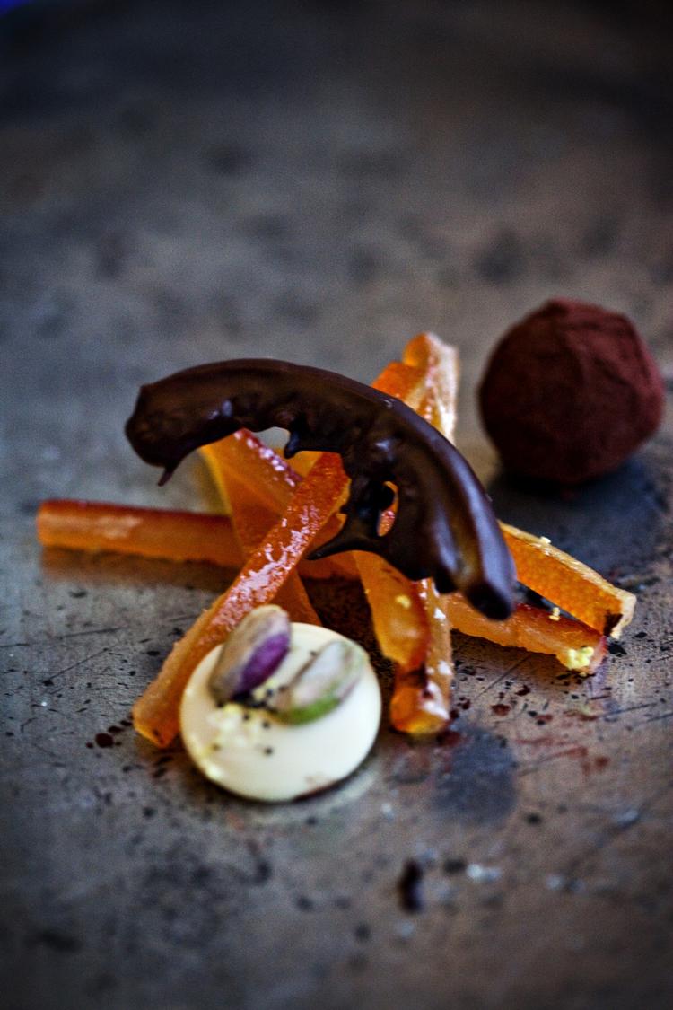 Rustikt. Hakkede appelsiner og mandler samles til en grov marcipan og dyppers herefter i tempereret chokolade. 