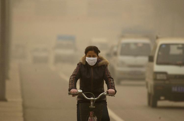 UDVIDELSE. Kvindelig cyklist trodser den synlige luftforurening i Lanzhou. Nu skal byen - en af Kinas mest forurenede - udvides ved at fjerne omkringliggende bjerge. 