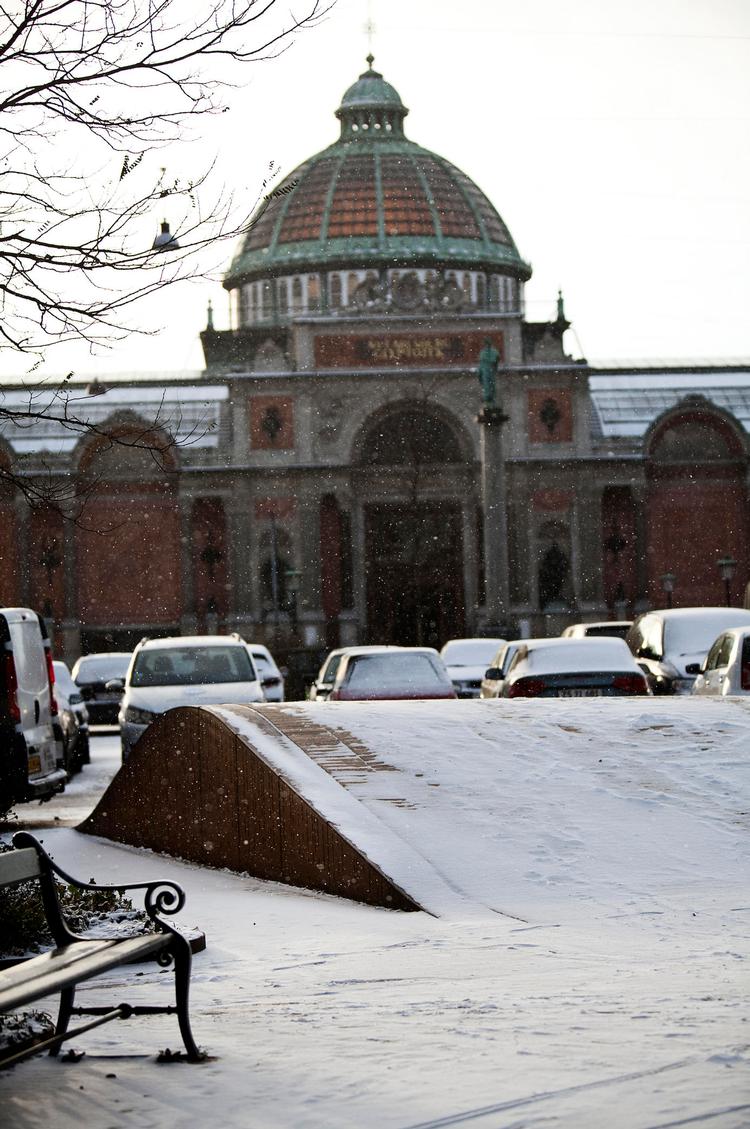 Sne. Gule teglsten gemmer sig under sneen på Dantes Plads, hvis tæppe løfter sig i små fine folder. 