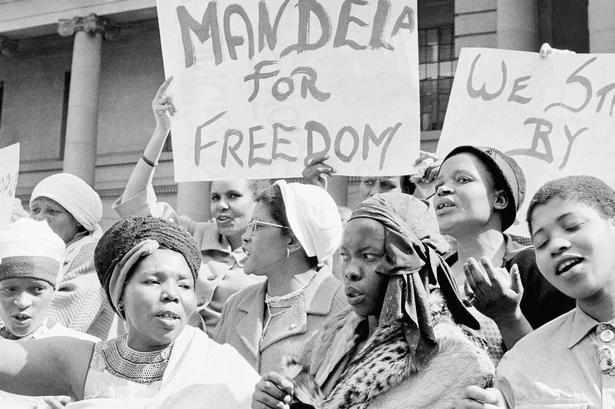 Efter Nelson Mandelas fængsling i 1962 demonstrerer hustruen Winnie Mandela sammen med andre kvinder foran rådhuset i Johannesburg. 