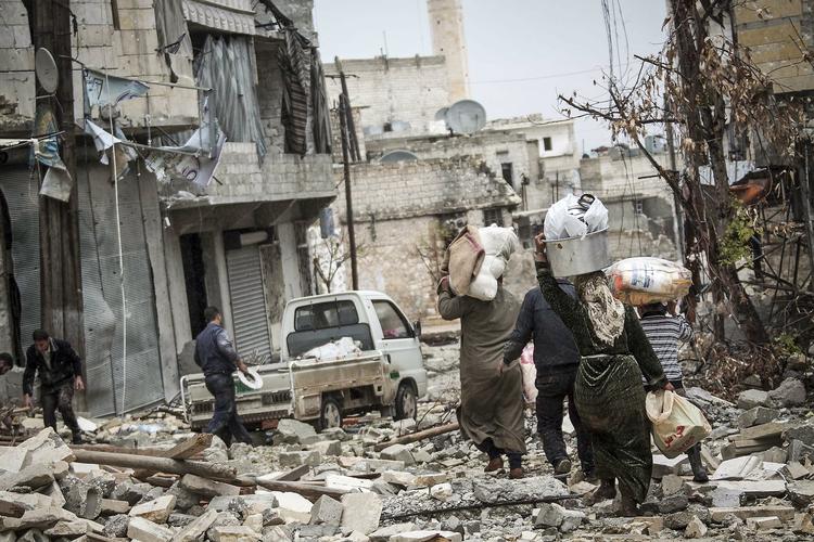 STRID. Indbyggere i Aleppo går gennem gade, hvis huse er voldsomt beskadigede af kampe mellem optørere og regeringstropper. 