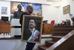 Bøn. En medarbejder på Venezuelas ambassade i Haiti gør klar til en messe, hvor de ansatte beder for den kræftsyge Hugo Chavez (på billedet). 