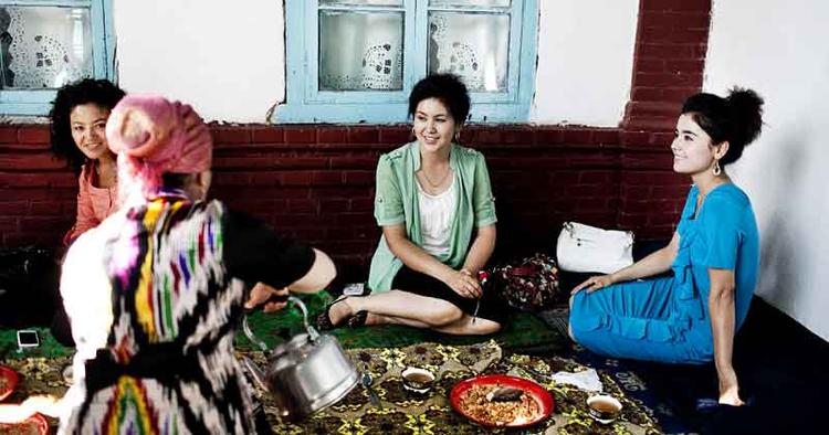 Ventetid. På en hævet terrasse i den overdækkede gård får kvinderne mad og te, mens de venter på, at deres veninde, bruden, bliver færdig. FOTO: Ditte Valente 