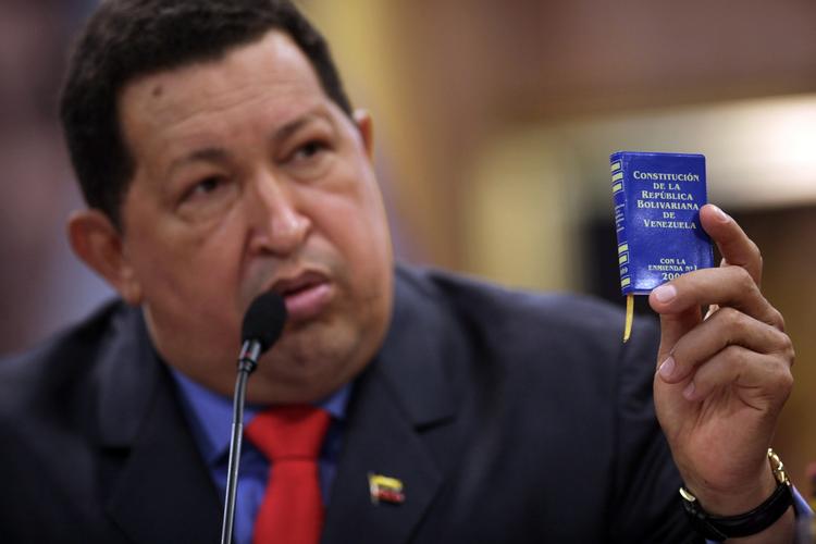 CHAVEZ. På billedet fra oktober ses Hugp Chavez stolt holde en miniature udgave af sit lands forfatning frem for folket. Den står nu - ifølge katolske biskopper - til ændring, hvis Chavez ikke bliver rask til at kunne tages i ed 10. januar. 