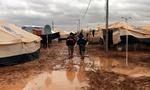 LEJRLIV. Syriske flygtninge går gennem mudderpølene i Zaatarilejren i Jordan. 