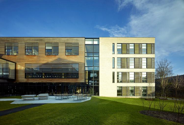 Sorte  metaller er med til at indramme de gule mursten og træet, der på facaden med tiden bliver gråt. Nederst til venstre aner man den ny elegante gangbro i glas og sort stål, der forbinder forhuset og nybygningen. 