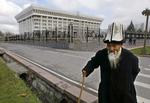 BORTFØRELSESFORBUD. Ældre kirgisisk herre med sin traditionelle kalpak på hovedet ud for regeringsbygningen i hovedstanden Bishkek. Nu har landets regering forbudt bruderov. 