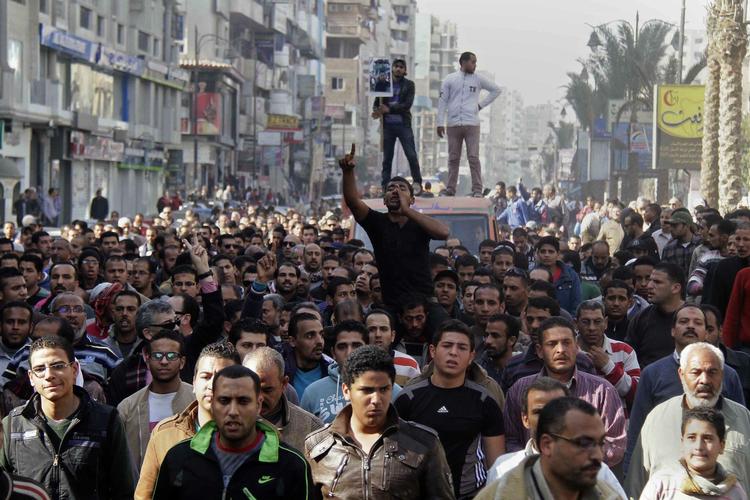 PROTEST. Tre omkomne fra weekendens demonstrationer begraves i Suez ved en højtidelighed lørdag, der illustrerer omfanget af protesterne mod styret. 