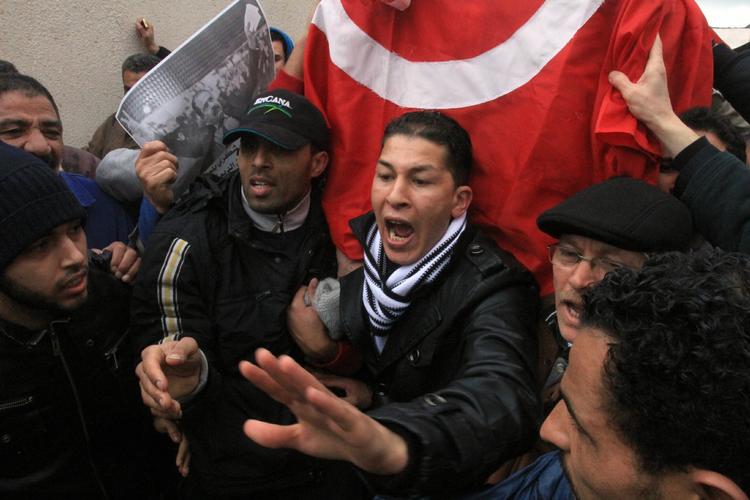 Sorg. Mens der er kampe i gaderne i Gafsa, er titusinder på gaden i Tunis for at begrave den dræbte oppositionsleder Chokri Belaid. Her sørger en af hans pårørende ved kisten. 