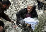 Borgerkrig. En syrisk mand bærer et barnelig ud af ruinerne efter et luftangreb i Aleppo. 