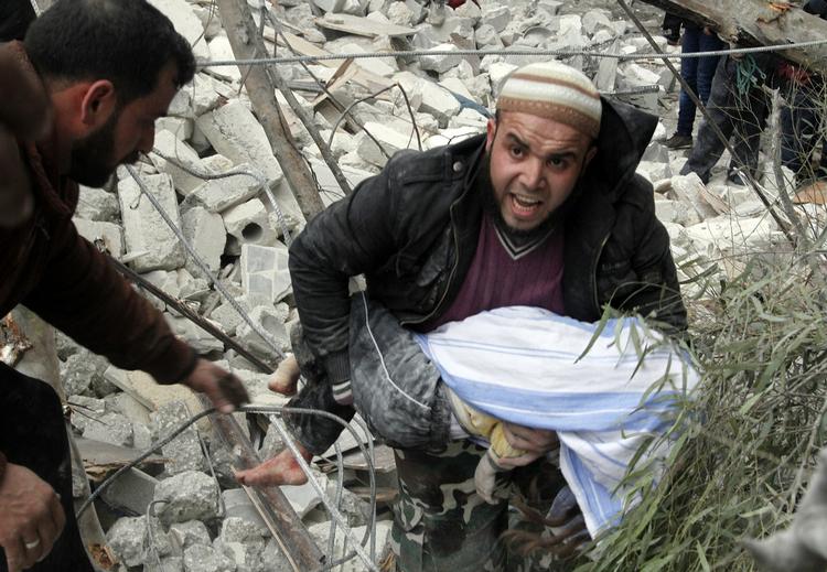 Borgerkrig. En syrisk mand bærer et barnelig ud af ruinerne efter et luftangreb i Aleppo. 