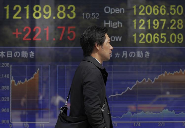 Opad. En japansk mand går forbi i en oversigt over aktierne, der viser fine plusser. 