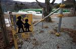 Et trafikadvarselsskilt står tilbage nær Tsushima Junior High School i Namie. I baggrunden har myndighederne oplagret forurenet jord. 