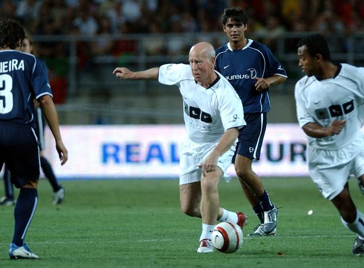 VM-guldvinder. Sir Bobby Charlton (midt) har trods sin efterhånden høje alder ikke helt glemt, hvordan den lille runde kugle skal spilles rundt på grønsværen. Det viser han her i 2004 i en velgørenhedskamp i Portugal. 