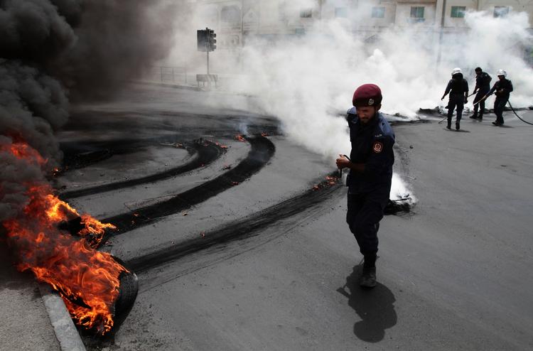 BALLADE. Oprørspoliti slukker ild i brændende bildæk, som er blevet tændt af bahrainske antiregeringsdemonstranter i byen Jidhafs i Bahrain. 