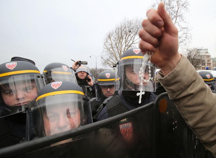 PROTEST. Modstander af homoseksuelle ægte skaber holder en rosenkrans op foran politifolk under en demonstration mod lovforslaget på Champs Elysee-boulevarden i Paris. 