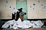Eftersøgning. På en skole nær den kollapsede  fabrik søger  pårørende at finde deres savnede. Mange er ligene er så svært tilredte, at de er svære at identificere. Samtidig er der så mange, der mangler at finde deres savnede, at der hurtigt  opstår tumult, når et nyt lig ankommer til skolen. 