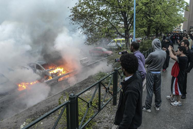 Uro. Beboere i forstaden Rinkeby følger med efter adskillige biler er stukket i brand. Området er et blandt flere stockholmske forstæder, som har været plaget af uro i den seneste uge. 