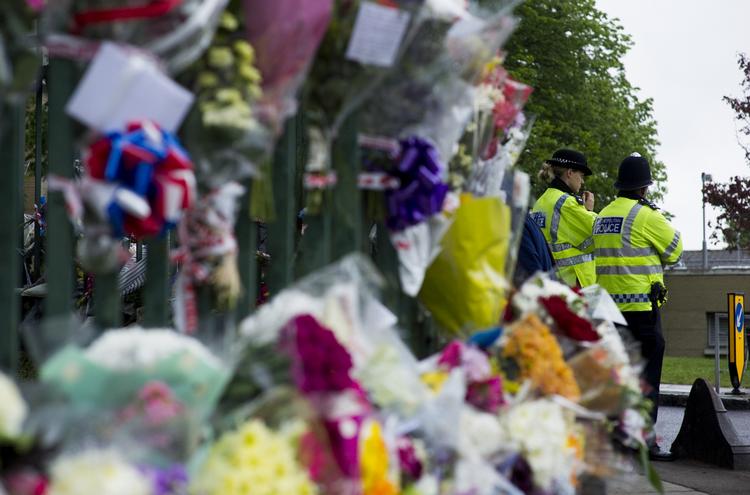 DRABSSTED. Betjente ved de mange blomsterdekorationer, Londonborgere har lagt på det sted, hvor to formodede islamister dræbte en soldat. 