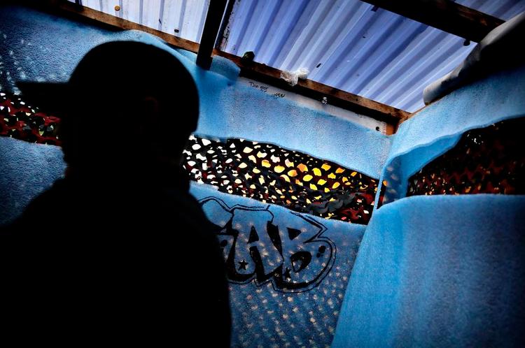 Pusher. En anonym pusher på arbejde under kasket i en hashbod bag kamouflagenet og isolationsmåtter. Med udsigt til Pusherstreet som nu går højsæsonen i møde. Foto: Martin Lehmann 