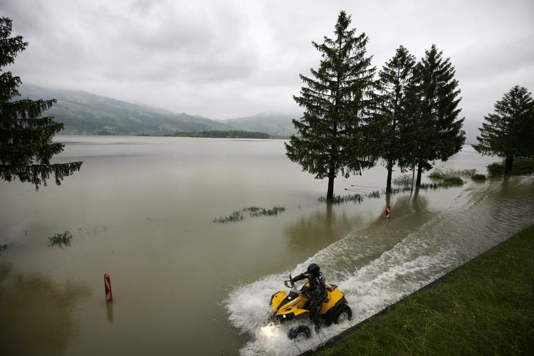 Firehjulet motorcykel på en oversvømmet vej ved Lauerzeesee i Schweiz. 