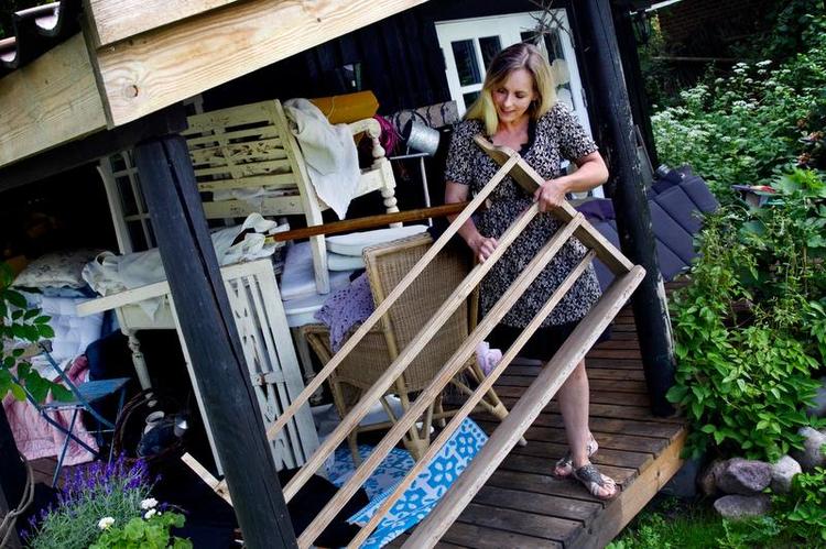hyldemeter. I et anneks i haven opbevarer Lene Siel gamle møbler, der venter på at blive sat i stand. Blandt andet tallerkenrækken, som hun vil male lys grå. Alt er netop rykket uden for, fordi rummet skal bruges til ældste datters studenterfest. Foto. Finn Frandsen 